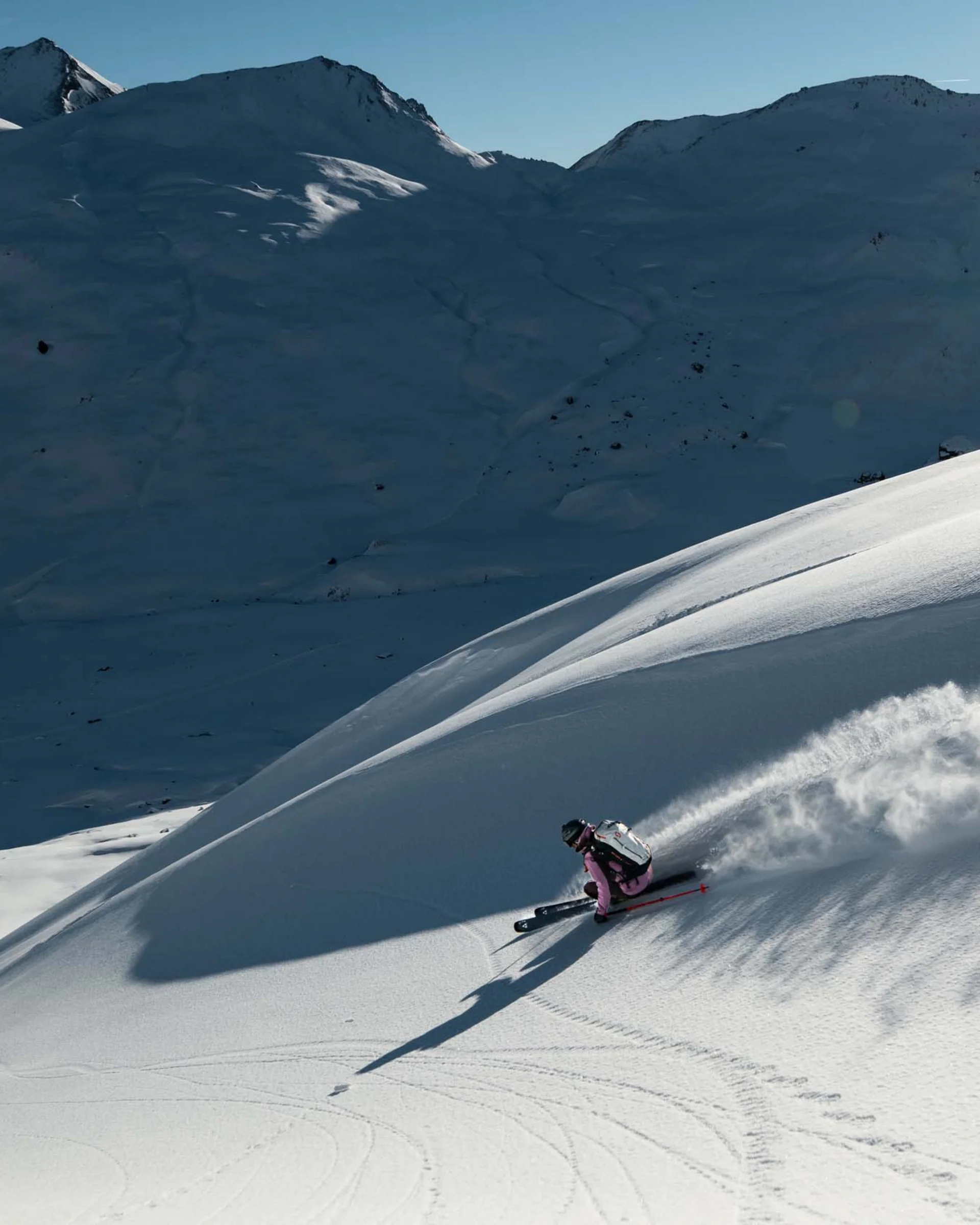 Impressionen | Hotel Alpenland in Ischgl Skifahrer fährt eine verschneite Bergflanke hinab, im Hintergrund schneebedeckte Gipfel