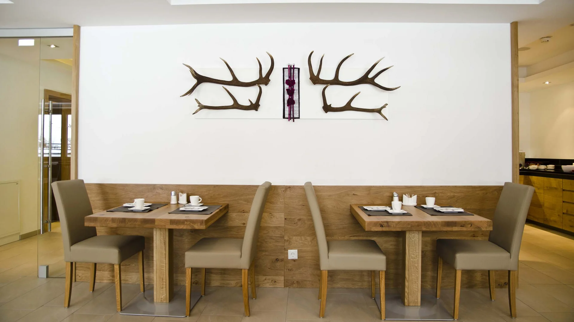 Alpenland: the hotel in Paznaun for your winter holiday Hotel restaurant with set wooden tables and antler wall decoration