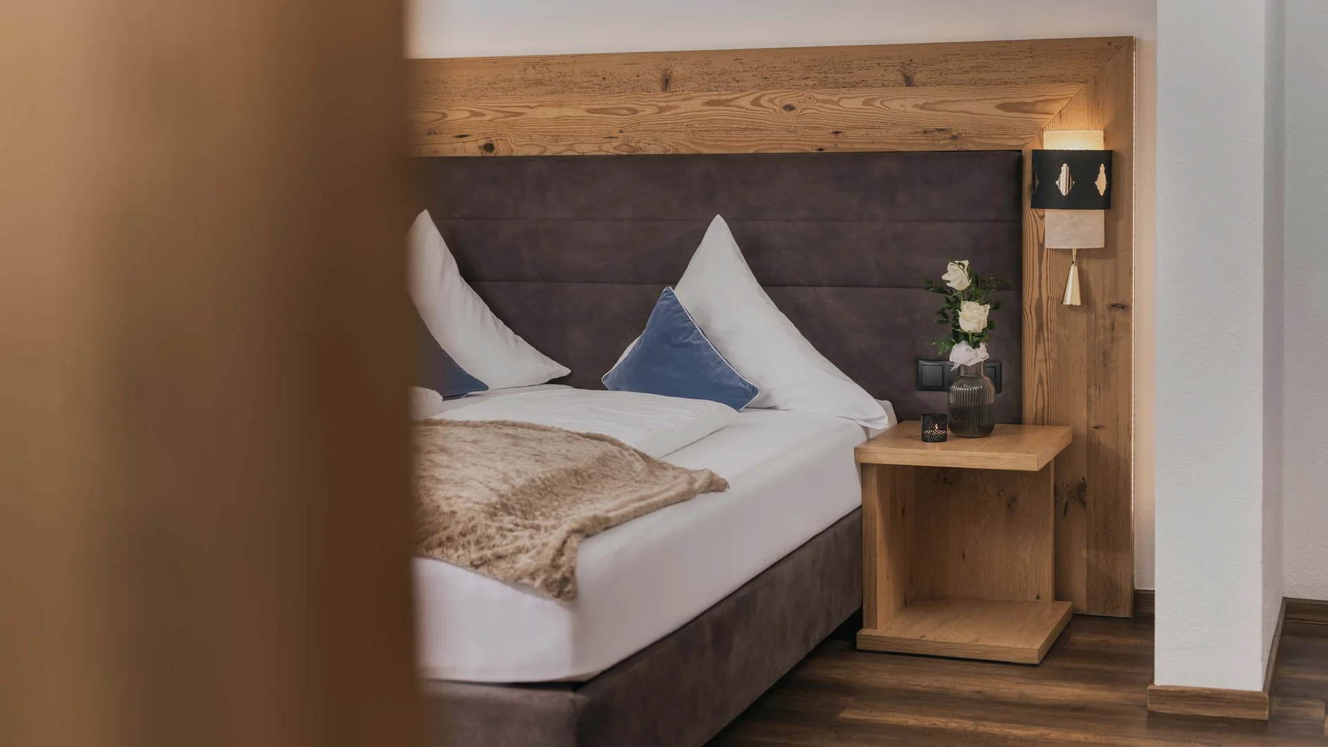 Ferienglück and Alpenland | Your stylish hotels in Ischgl Cozy hotel room with double bed, wooden headboard and bedside table