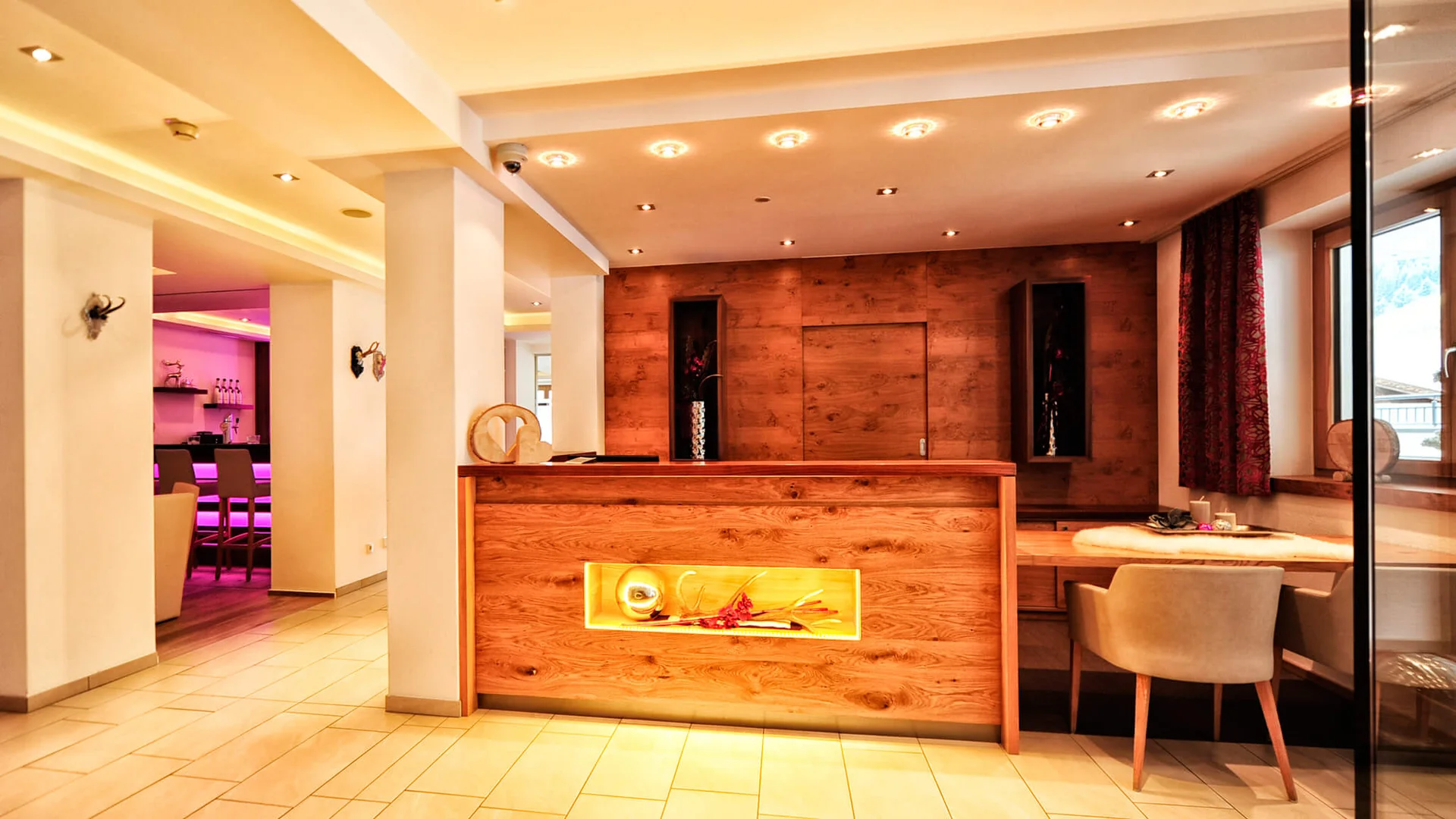Alpenland: the hotel in Paznaun for your winter holiday Hotel reception with wooden desk, seating area and illuminated bar area