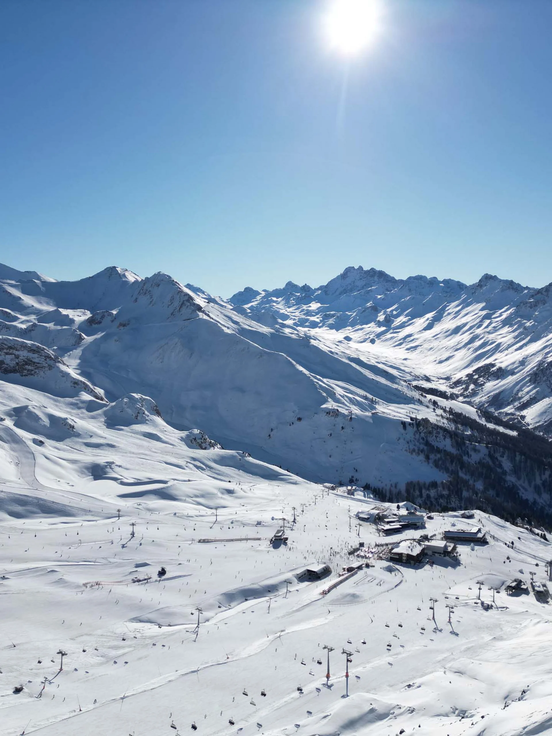 Impressionen | Hotel Alpenland in Ischgl Verschneite Berglandschaft mit Skigebiet und Sesselliften unter blauem Himmel