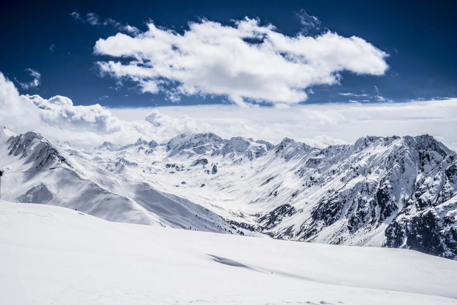 Impressionen | Hotel Alpenland in Ischgl Verschneite Berglandschaft unter blauem Himmel mit weißen Wolken