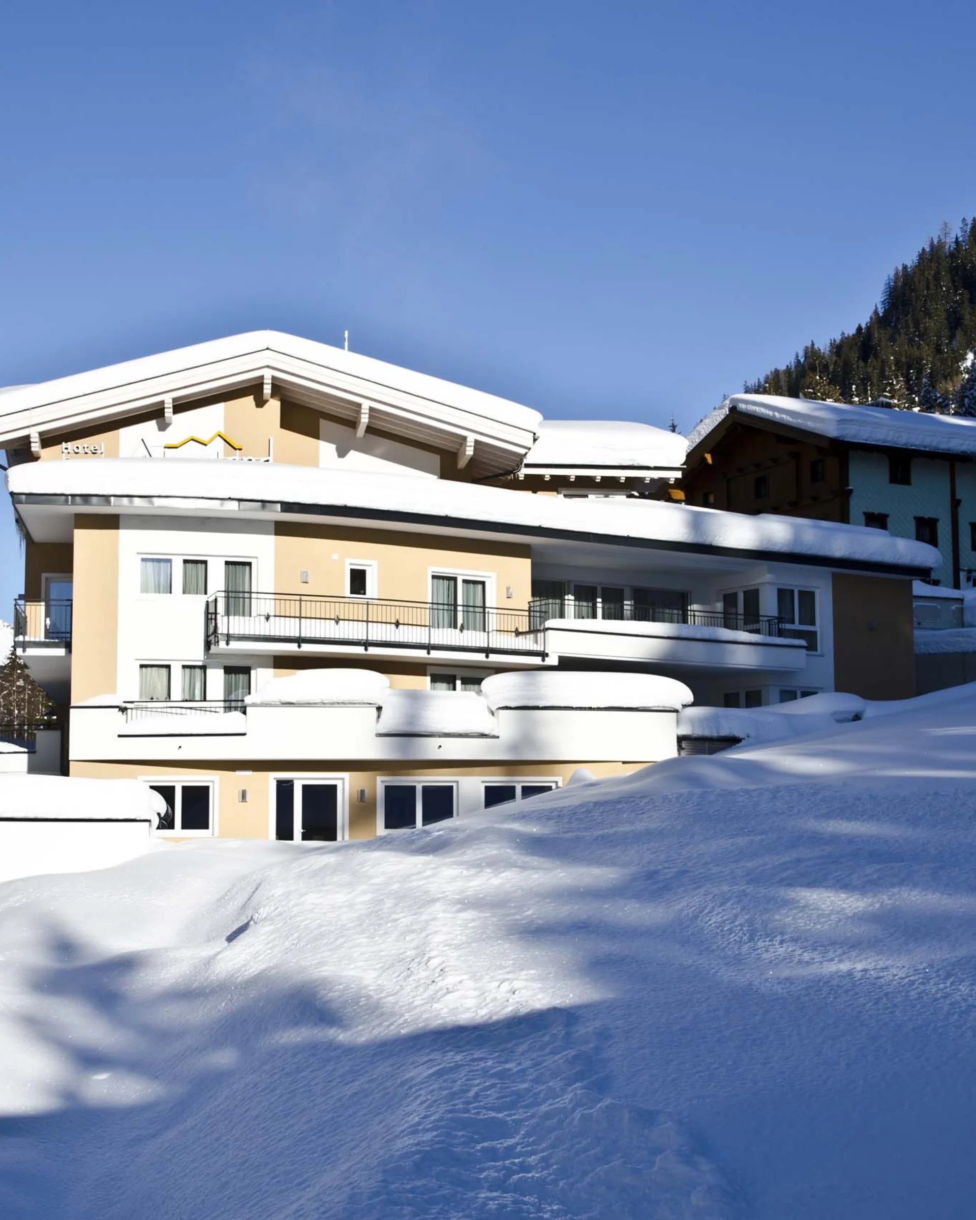 Impressionen | Hotel Alpenland in Ischgl Verschneites Hotel in den Bergen bei strahlend blauem Himmel