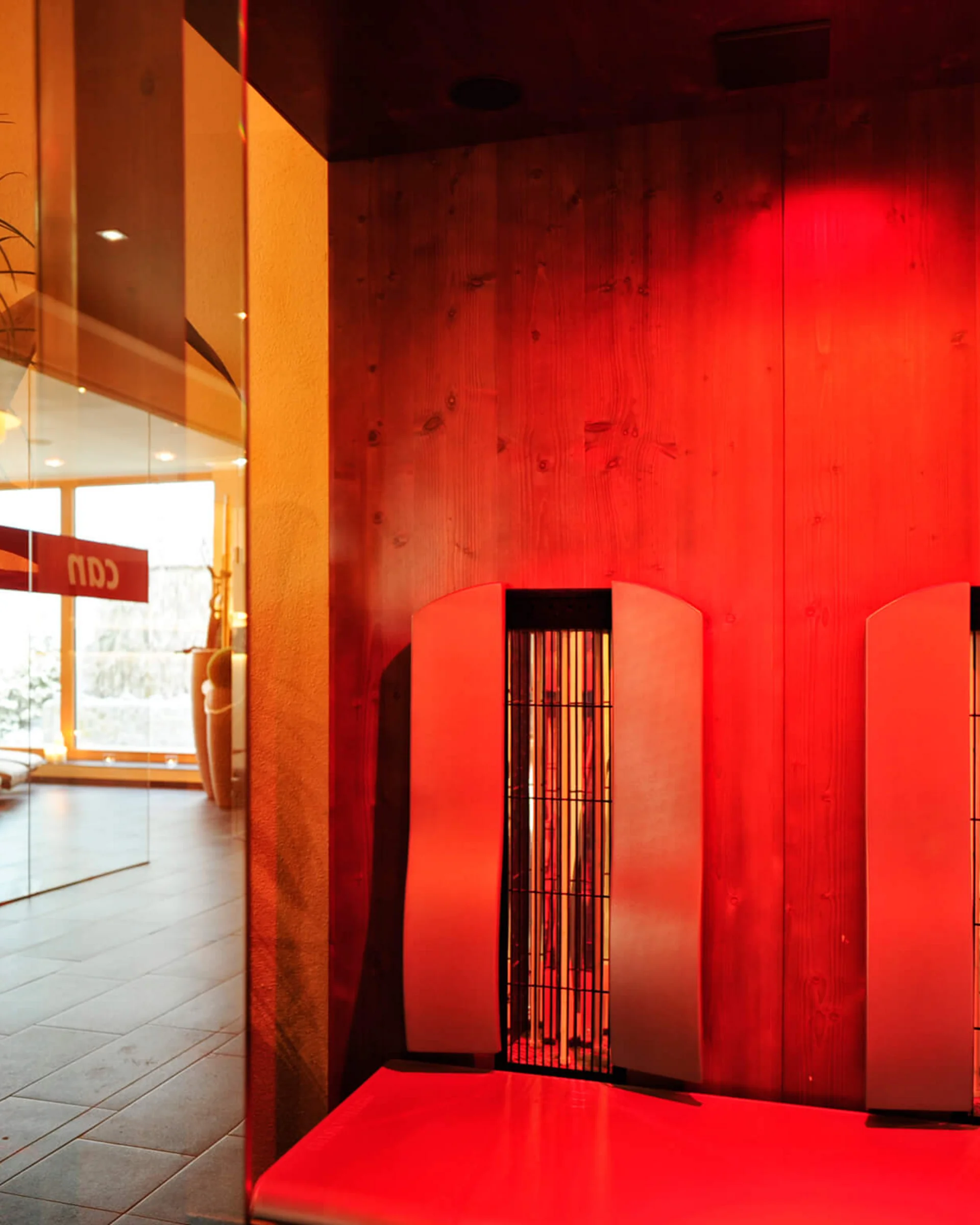 Impressionen | Hotel Alpenland in Ischgl Rot beleuchteter Innenbereich mit zwei hohen vergitterten Leuchten