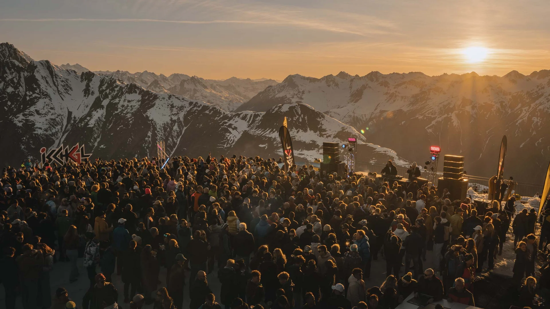 Impressionen | Hotel Alpenland in Ischgl Menschenmenge bei einem Konzert vor verschneiten Alpen im Sonnenuntergang