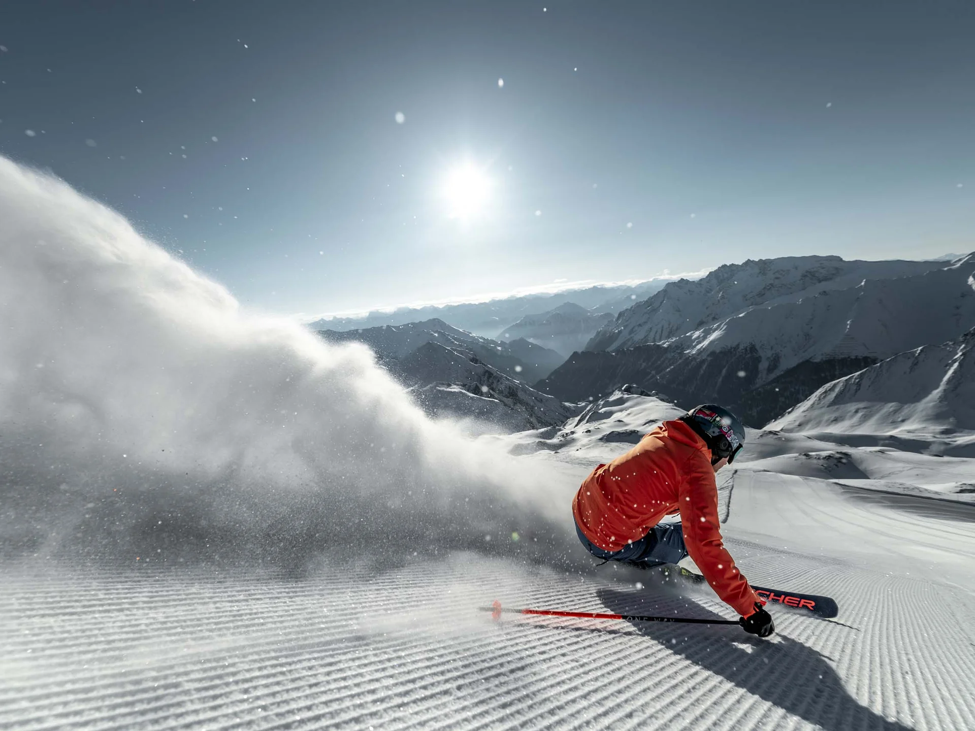 Impressionen | Hotel Alpenland in Ischgl Skifahrer in roter Jacke auf verschneiter Piste vor Bergpanorama