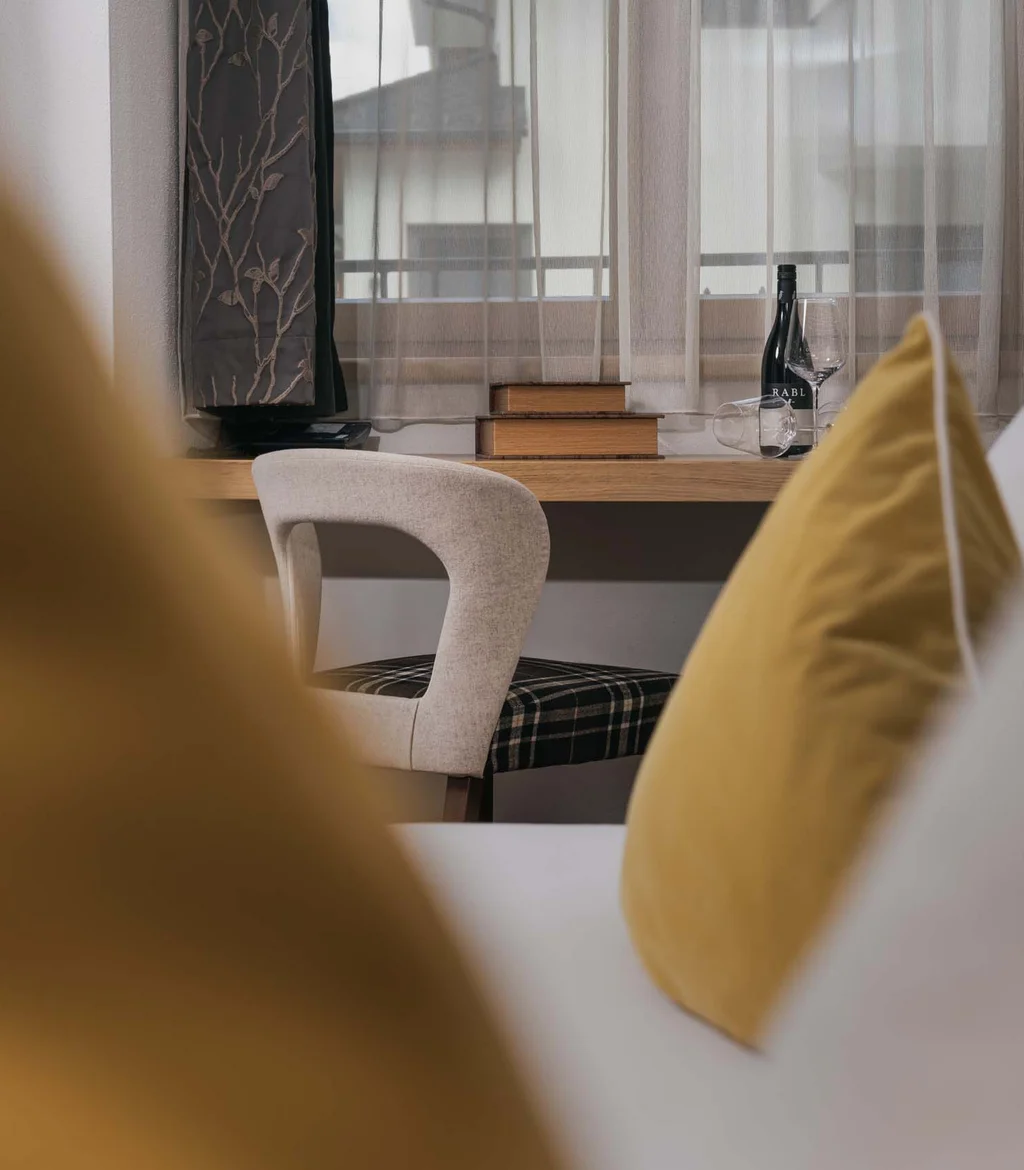 Ferienglück and Alpenland | Your stylish hotels in Ischgl Cozy room with yellow cushions, desk and armchair by the window