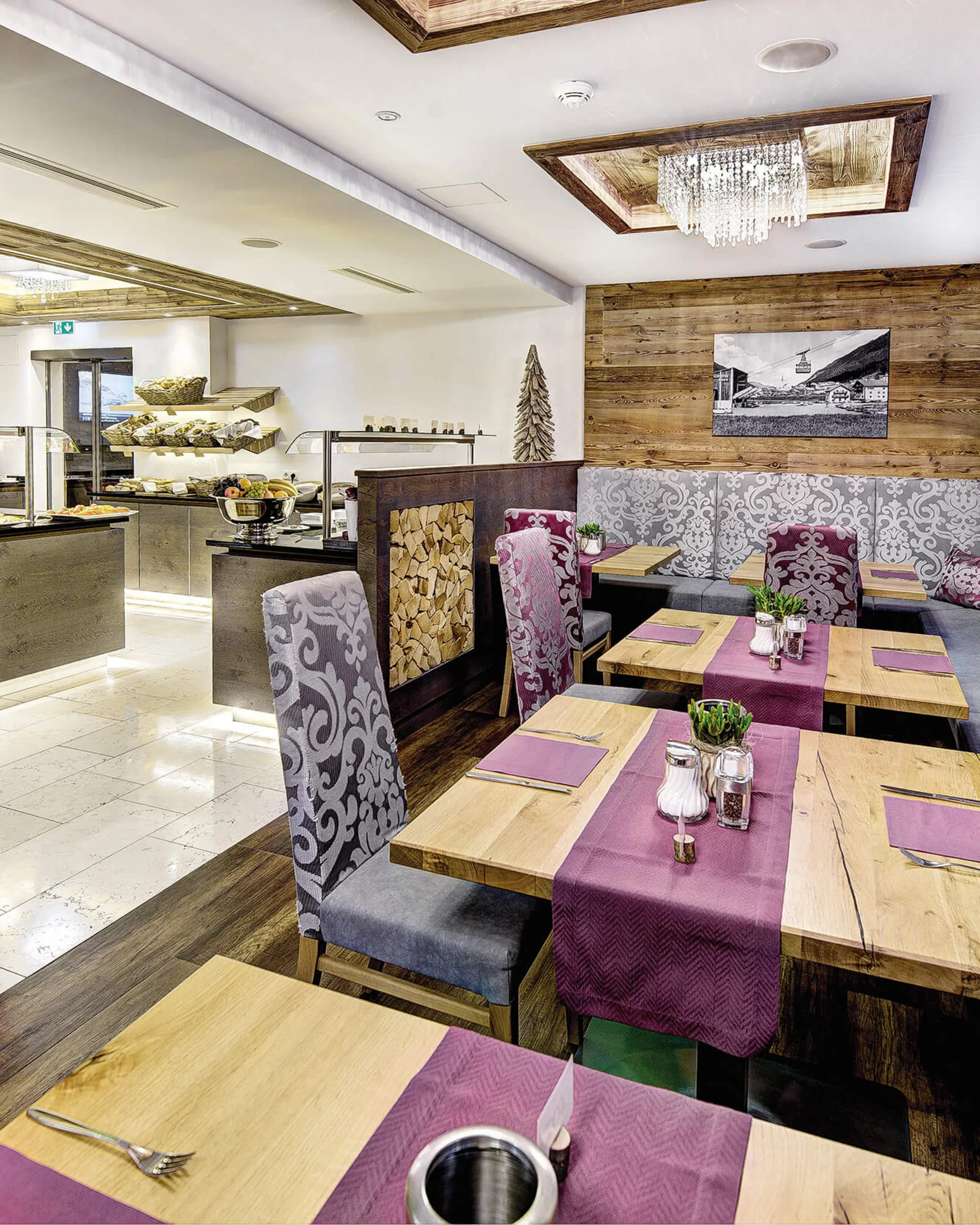 Ferienglück and Alpenland | Your stylish hotels in Ischgl Rustic restaurant with fireplace, wooden tables and patterned bench seating