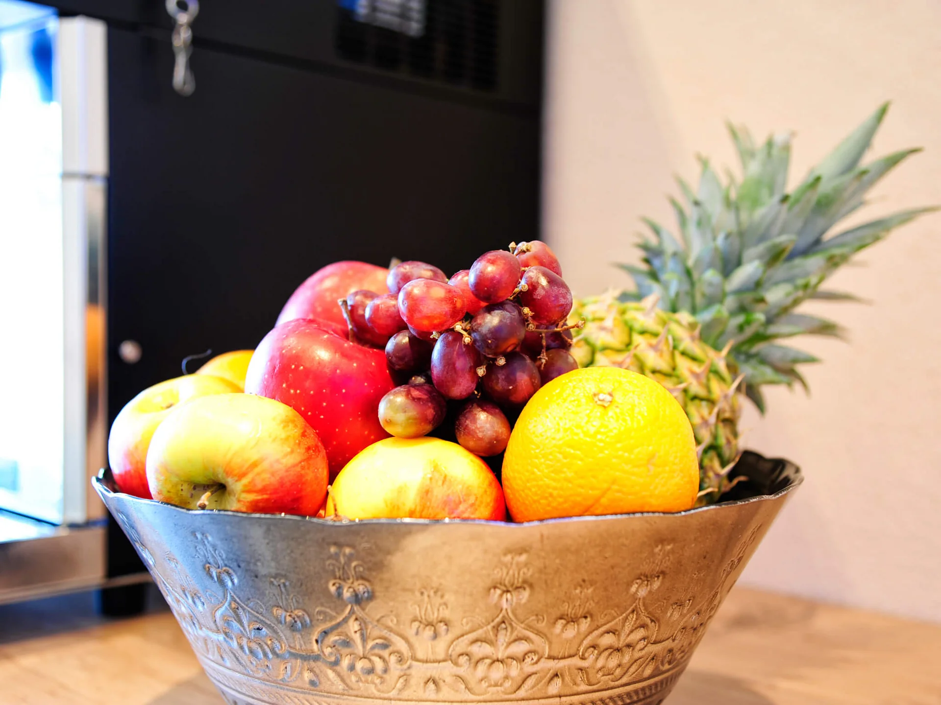 Impressionen | Hotel Alpenland in Ischgl Schale mit Äpfeln, Trauben, Orangen und Ananas auf einem Tisch