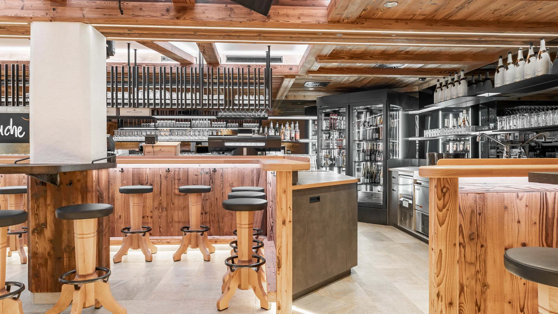 Ferienglück and Alpenland | Your stylish hotels in Ischgl Rustic bar with wood paneling, stools, shelves and beverage coolers
