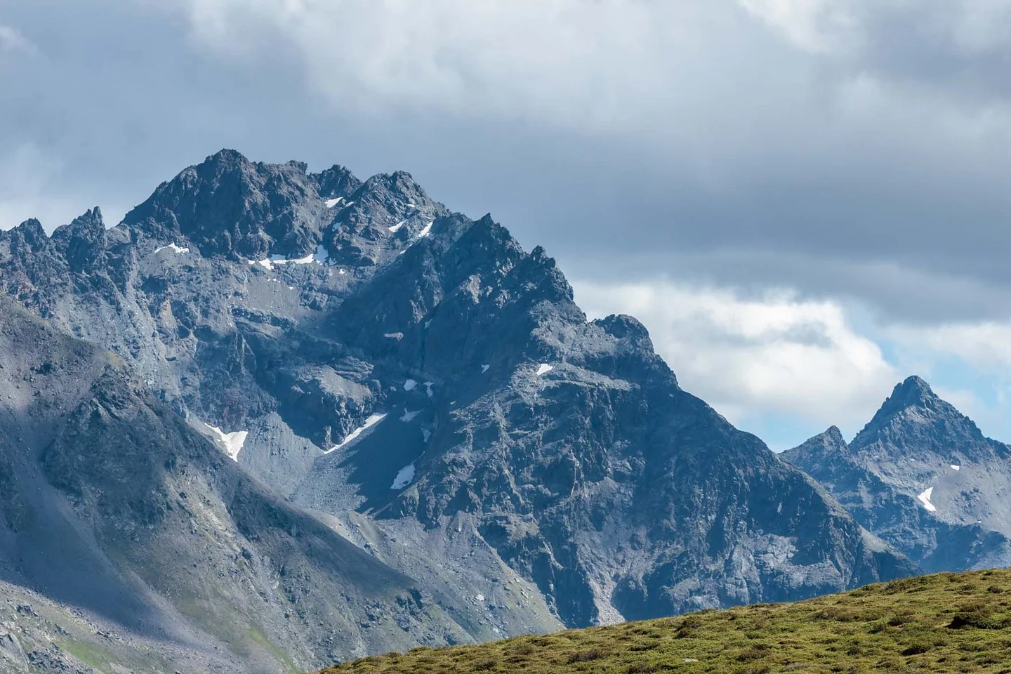 Ferienglück and Alpenland | Your stylish hotels in Ischgl Hikers on a mountain trail before a rugged, partly snow-covered mountain range