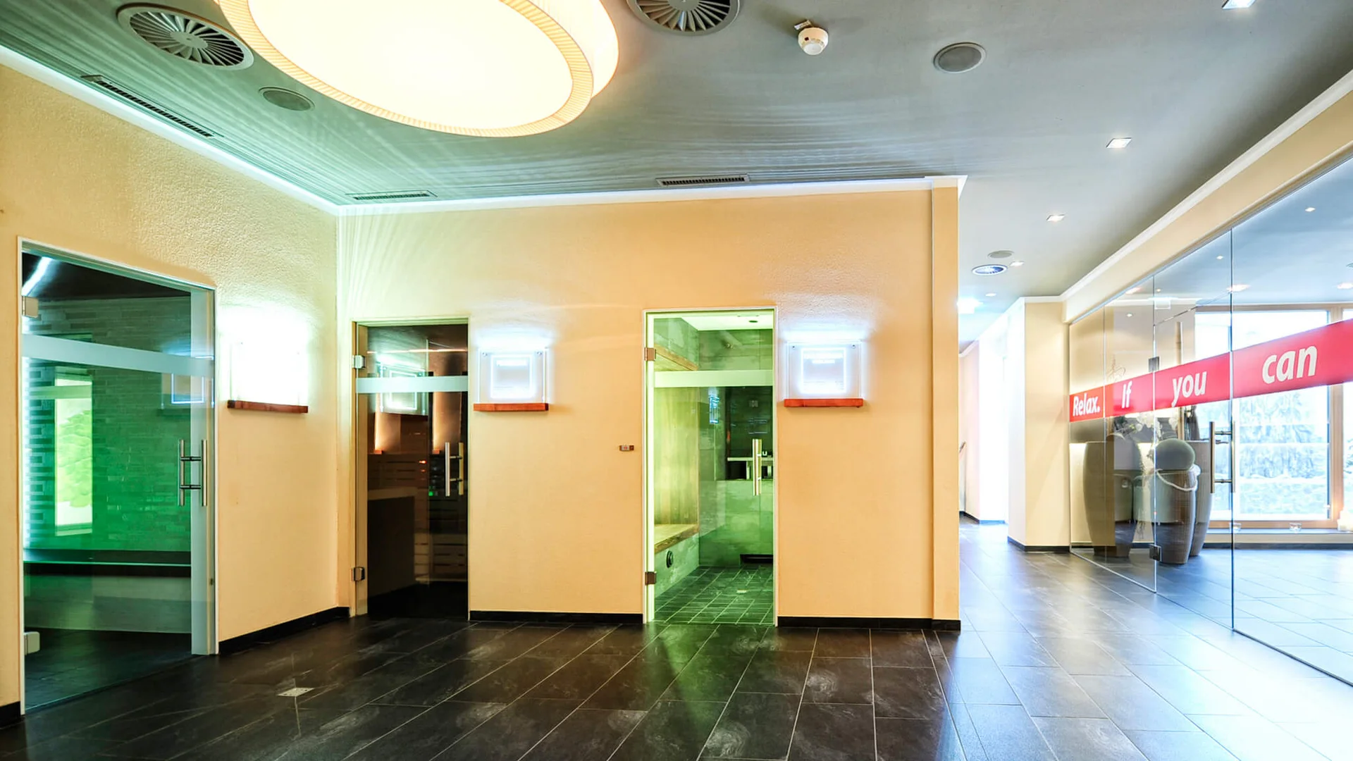Impressionen | Hotel Alpenland in Ischgl Heller Innenbereich mit drei verglasten Kabinen und schwarzem Fliesenboden